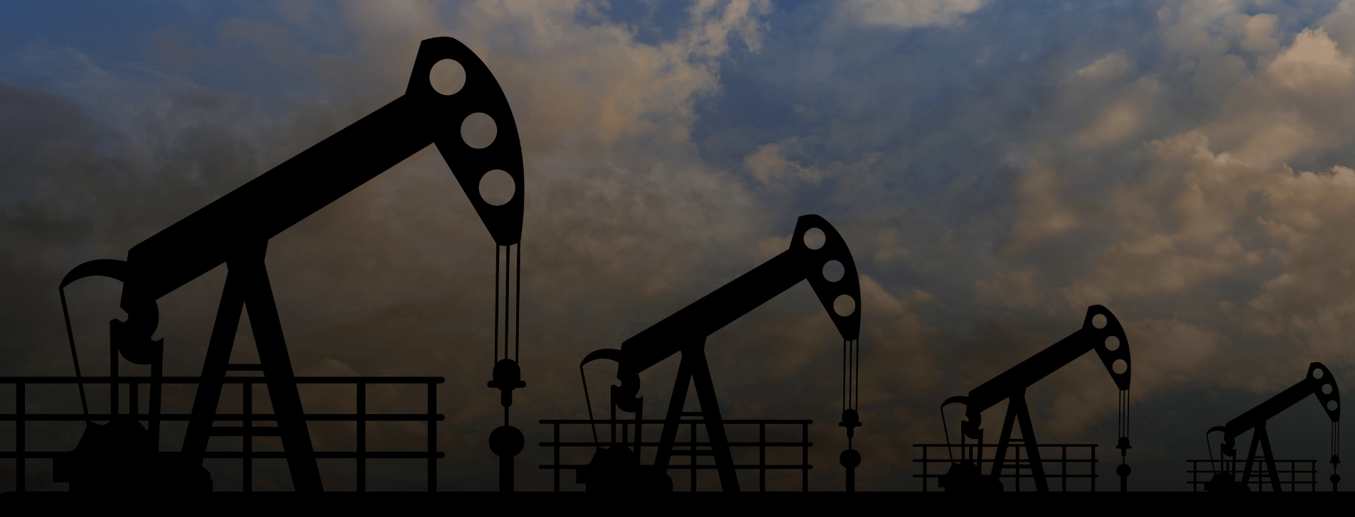 Four Oil drills in a row against a partly cloudy sky