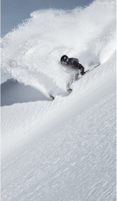 Person skiing down a mountain leaving behind a plume of snow