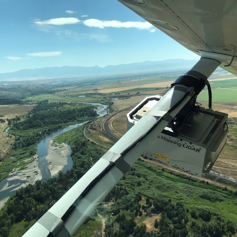 Gas Mapping LIDAR device attached to plane flying over river and green fields